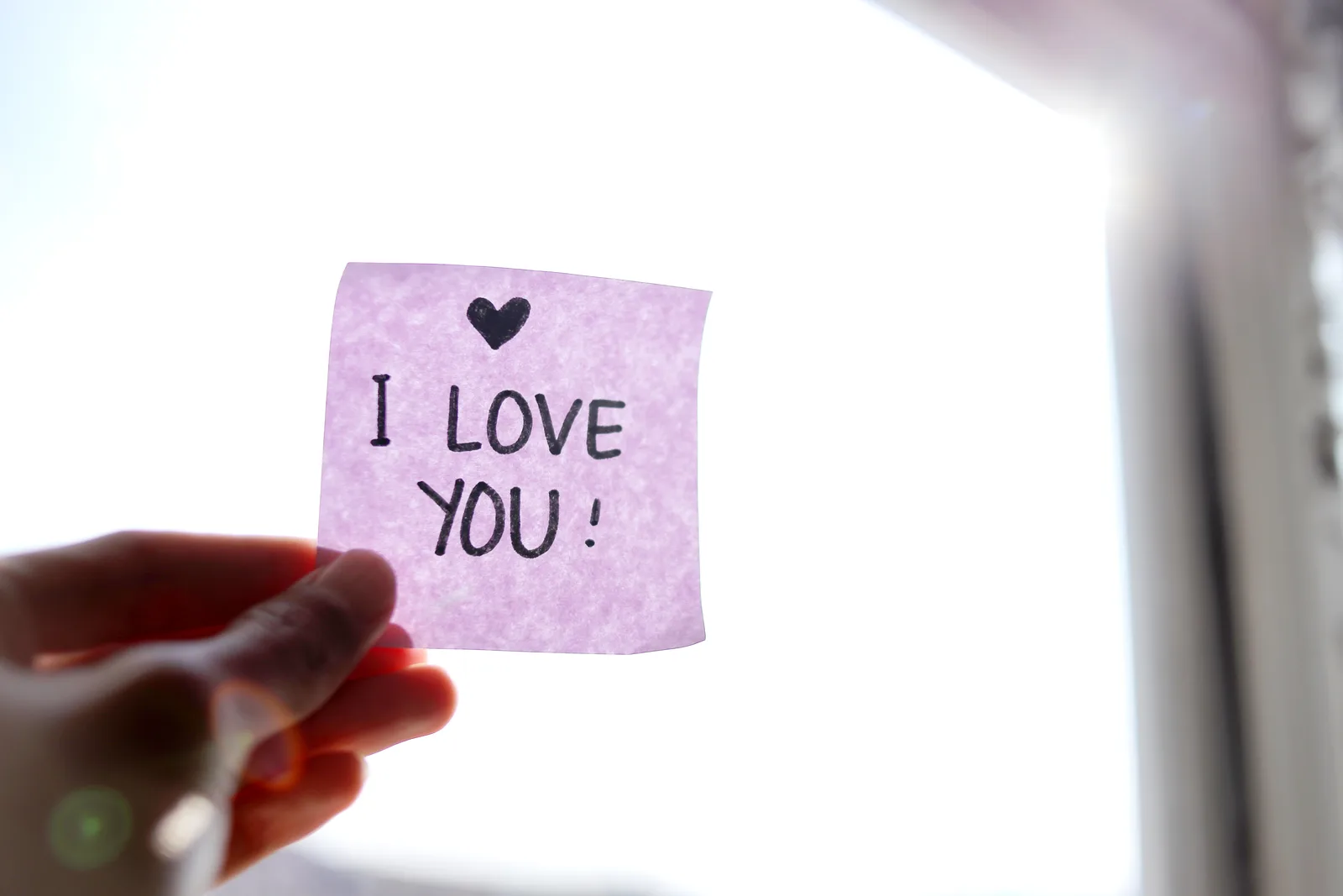 Ruka drží lístek s nápisem I love you jako vzkaz na zrcadle