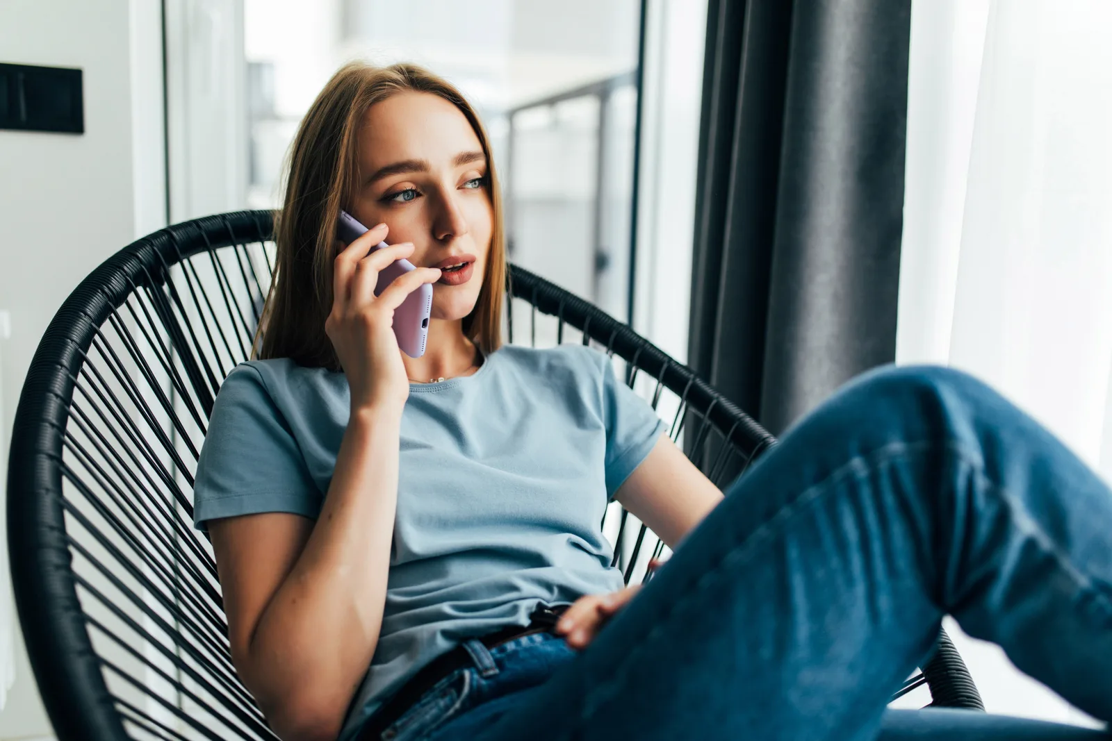 Žena sedí u okna a telefonuje, láska na dálku každý večer